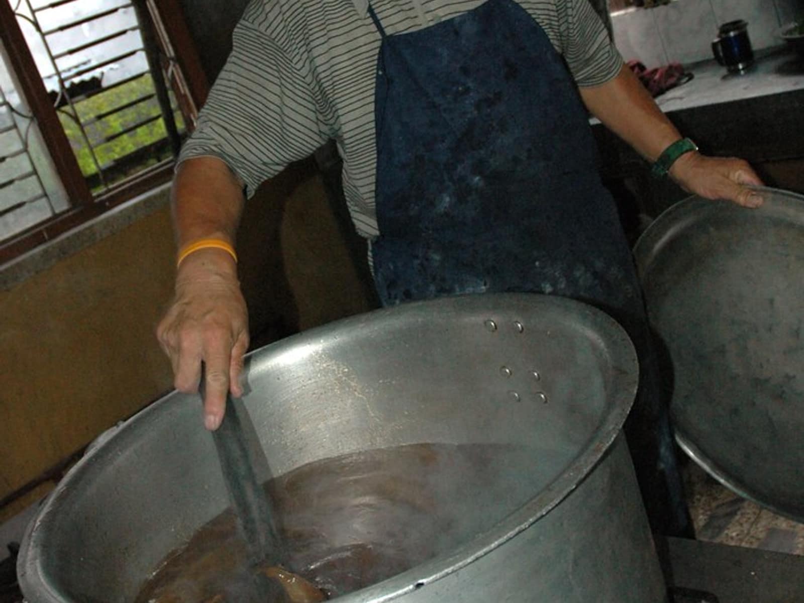 A cook stirring vegetables in a large pot in a catering kitchen.